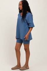 woman wearing a blue oversized t-shirt with matching bike shorts and beige slip-on shoes