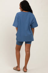 woman wearing a loose-fitting blue oversized t-shirt and matching blue shorts, standing with back to the camera