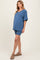 woman wearing a blue oversized v-neck maternity top and matching bike shorts, showing her baby bump