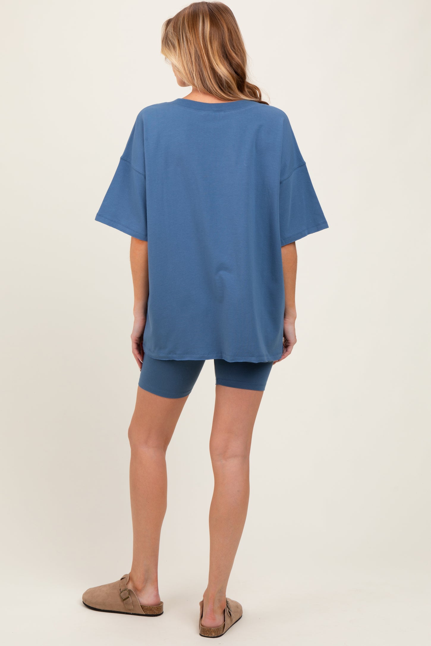 woman wearing a blue oversized t-shirt and matching bike shorts, showcasing a relaxed maternity outfit from the back
