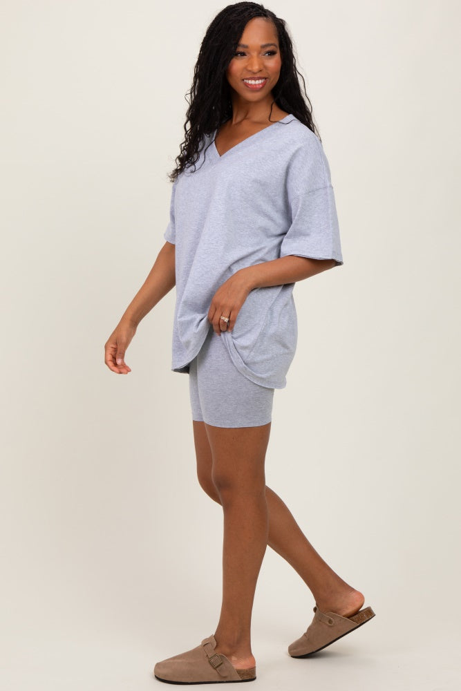 woman wearing a gray oversized v-neck t-shirt and matching shorts, paired with slip-on slides