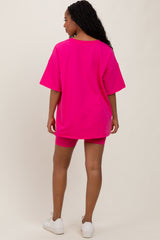 woman wearing a bright pink oversized t-shirt and matching shorts, viewed from the back