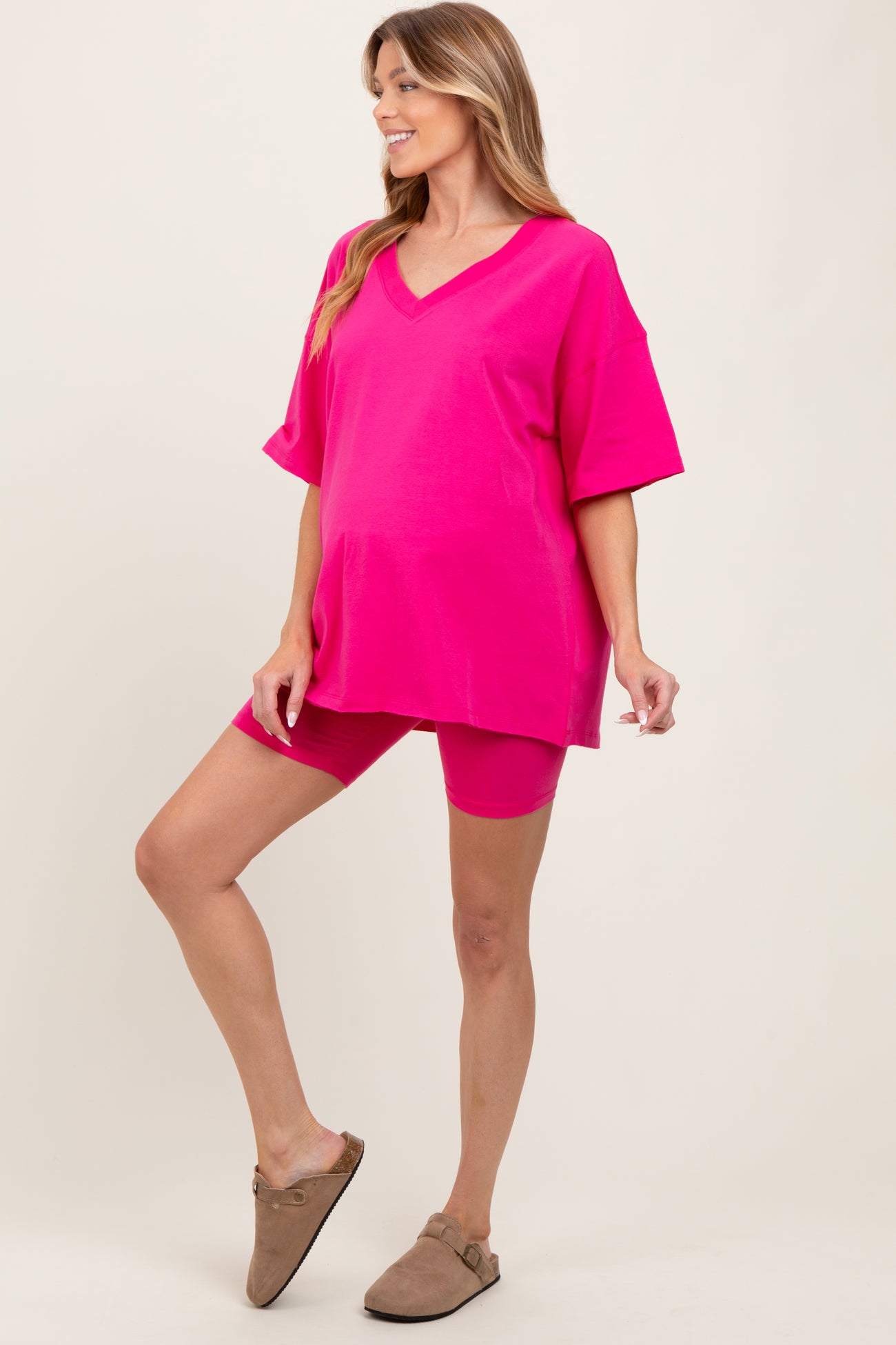 woman wearing a bright pink maternity short sleeve top and matching shorts, showing her baby bump
