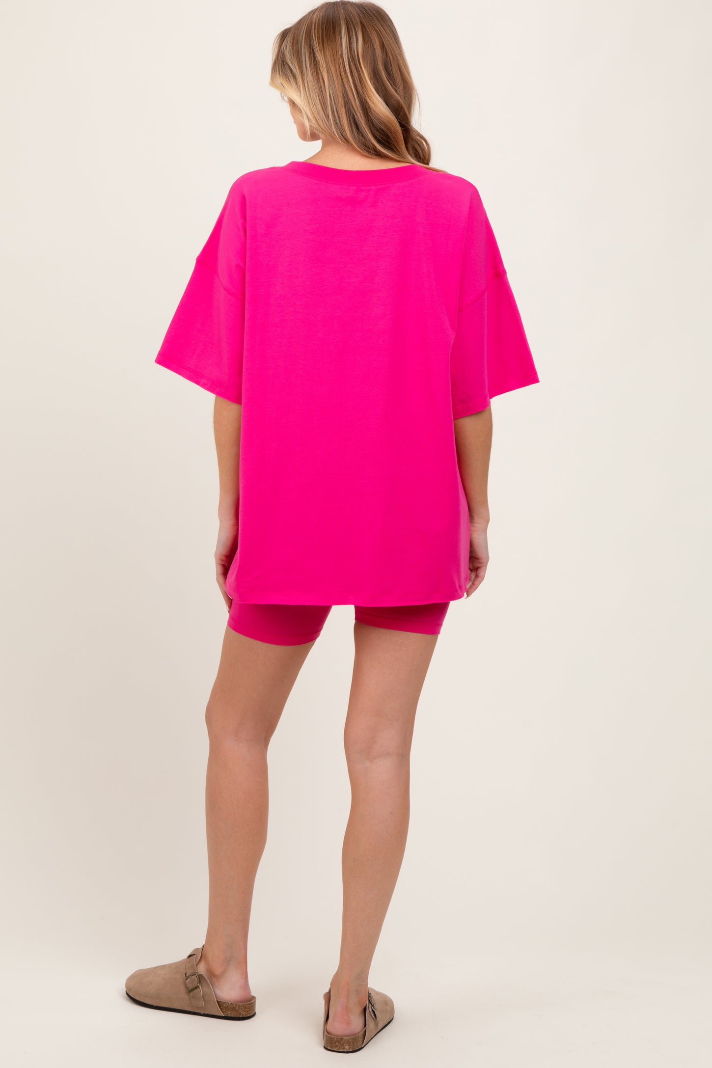 woman wearing a hot pink oversized maternity t-shirt with matching shorts, showing a relaxed fit suitable for maternity wear
