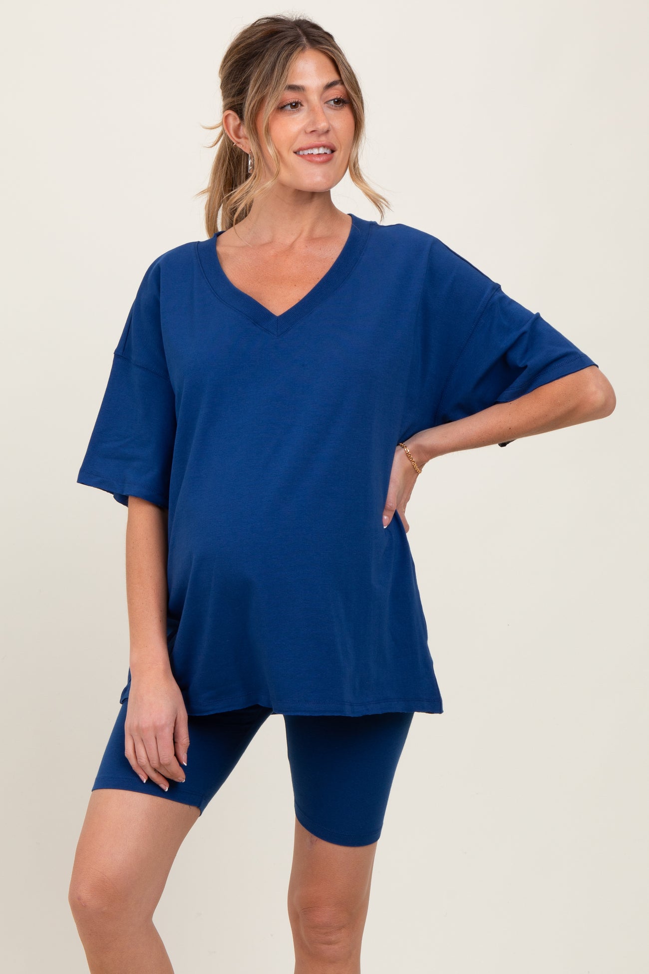 woman wearing a navy blue maternity oversized v-neck tee and matching bike shorts, showing her baby bump