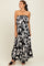 woman wearing a black and white patterned strapless maxi dress with ruffled details and wedge sandals