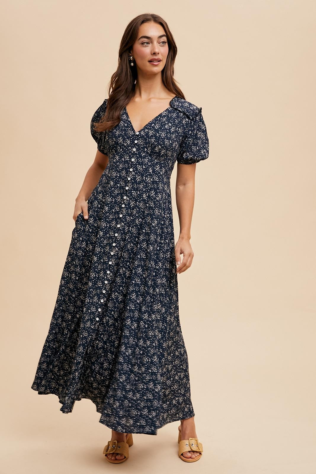 woman wearing a navy blue floral print maxi dress with puff sleeves and a v-neckline