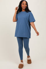woman wearing a blue oversized t-shirt and matching leggings, paired with cozy slippers, standing and smiling