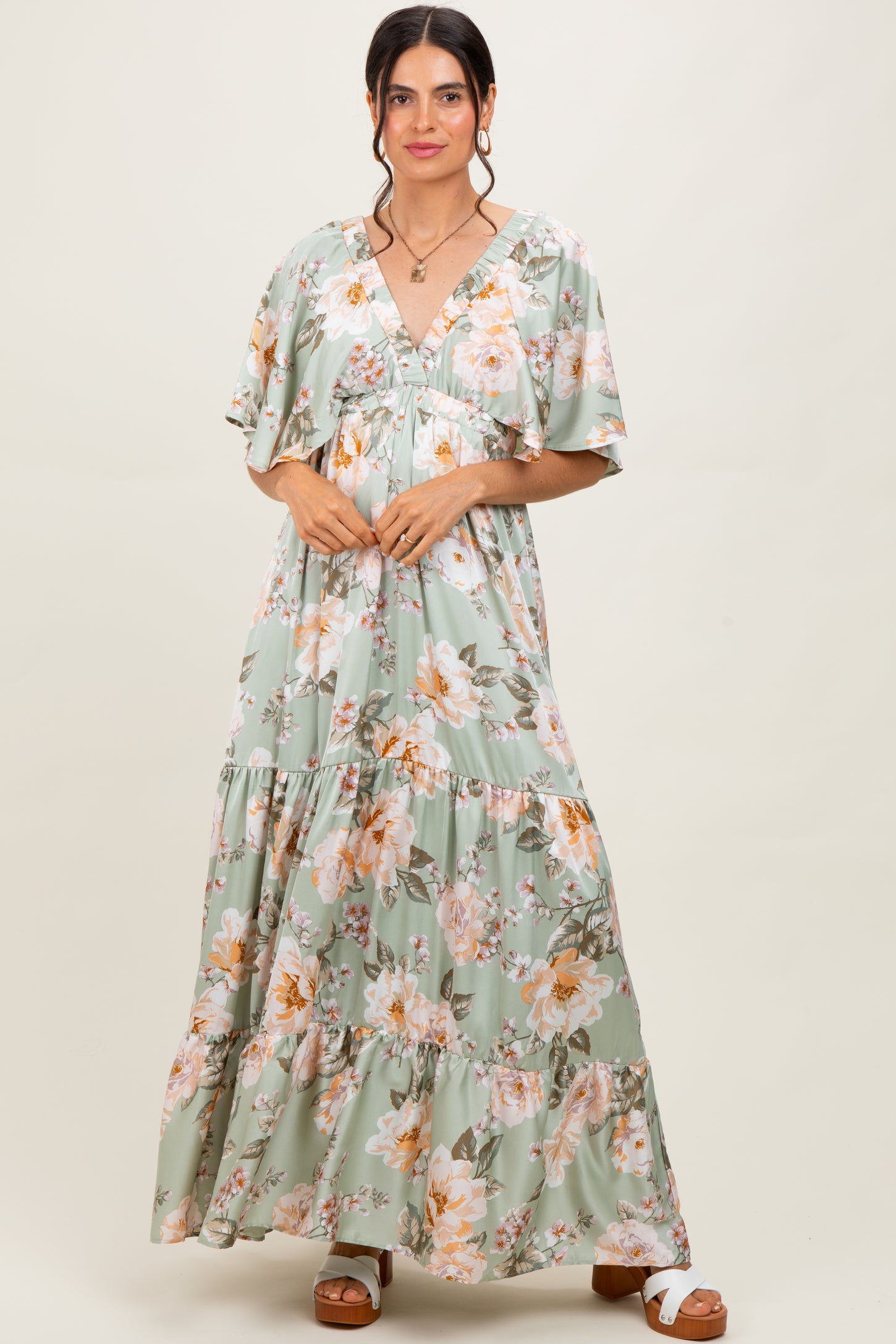 woman wearing a green floral maxi dress with short sleeves and a tiered skirt