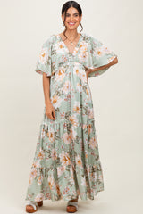 woman wearing a green floral maxi dress with flutter sleeves and a tiered skirt