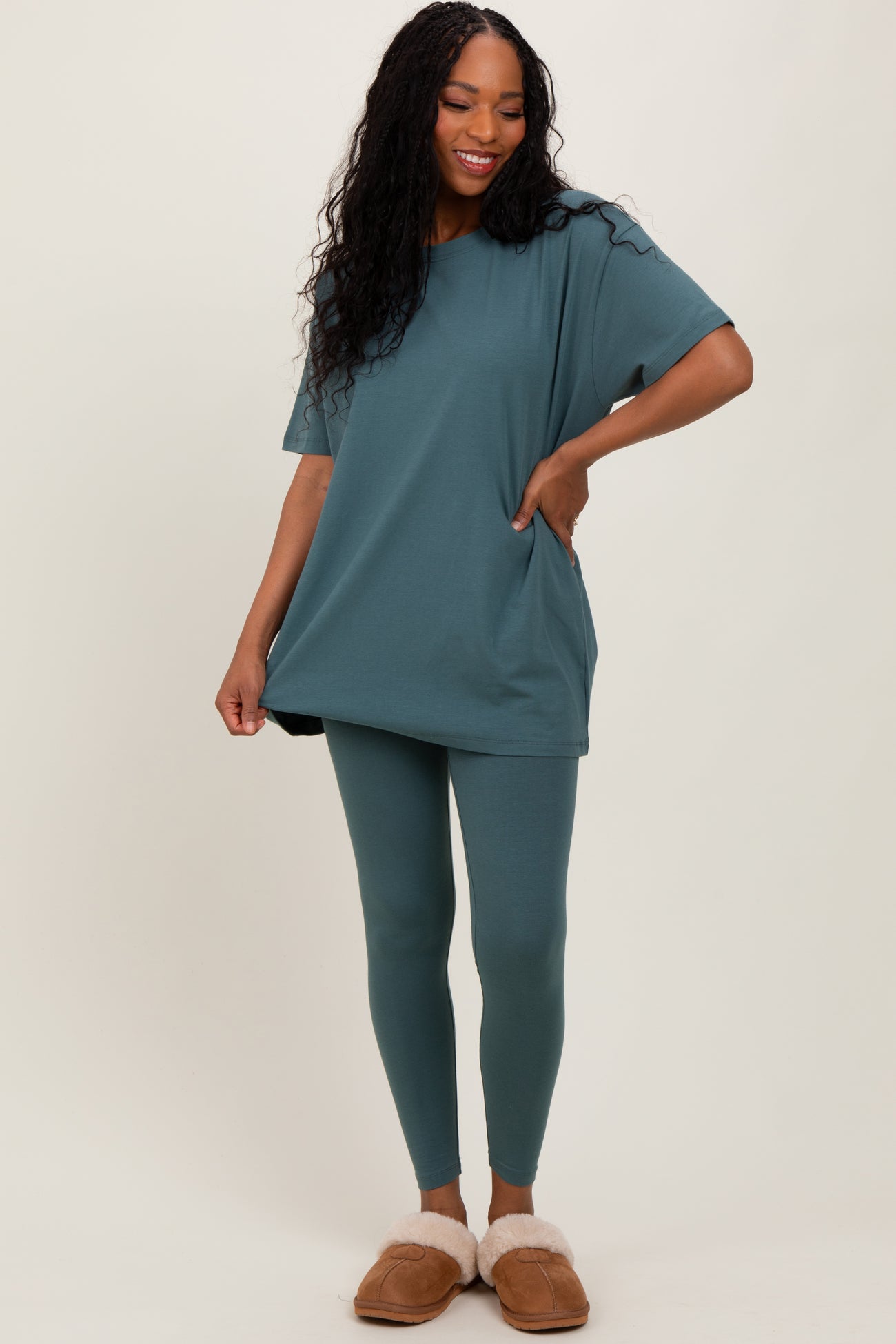 woman wearing a teal oversized t-shirt and matching leggings with pockets, styled casually with fuzzy slippers