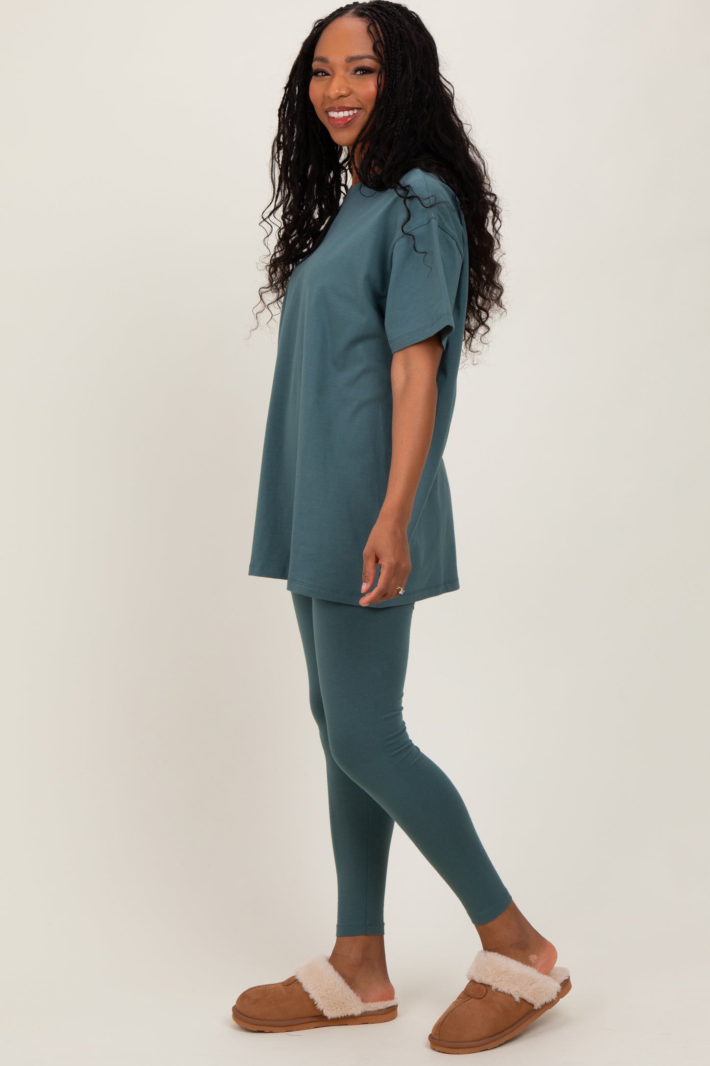 woman wearing a teal oversized t-shirt and matching leggings with brown fuzzy slippers