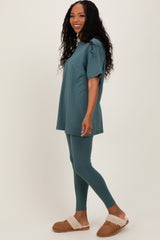 woman wearing a teal oversized t-shirt and matching leggings with brown fuzzy slippers
