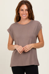 woman wearing a taupe short sleeve t-shirt with rolled sleeves and a relaxed fit