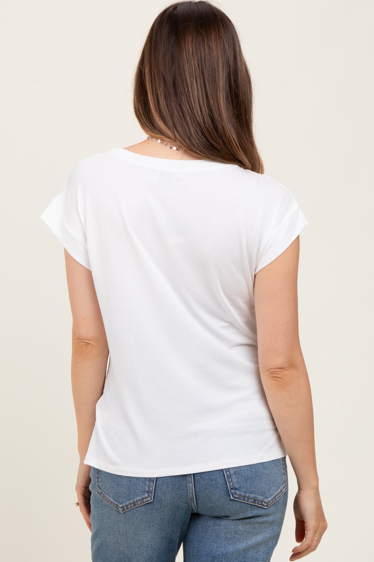 woman wearing a white short sleeve maternity top, showing the back view with relaxed fit and rolled sleeves