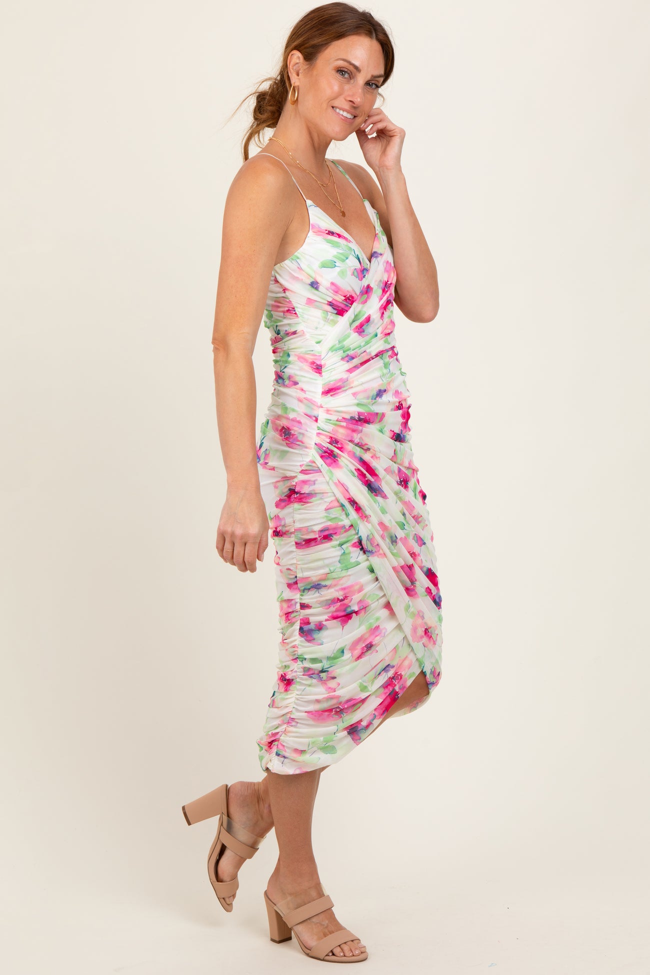 woman wearing a multicolored floral print bodycon dress with ruching and a knee-length hemline