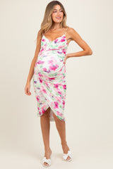 woman wearing a white floral maternity dress with a fitted silhouette and a side slit, highlighting her baby bump