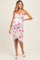 woman wearing a white floral maternity dress with a fitted silhouette and a side slit, highlighting her baby bump