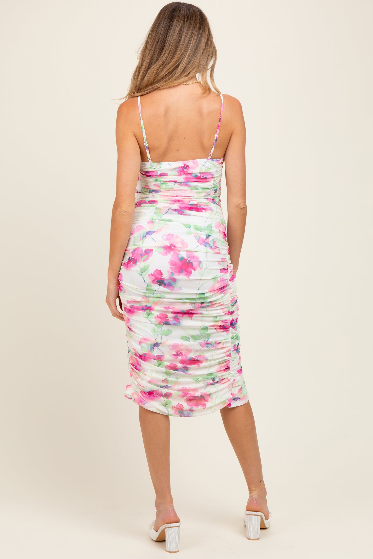 woman wearing a floral ruched maternity dress with adjustable straps, showing the back view