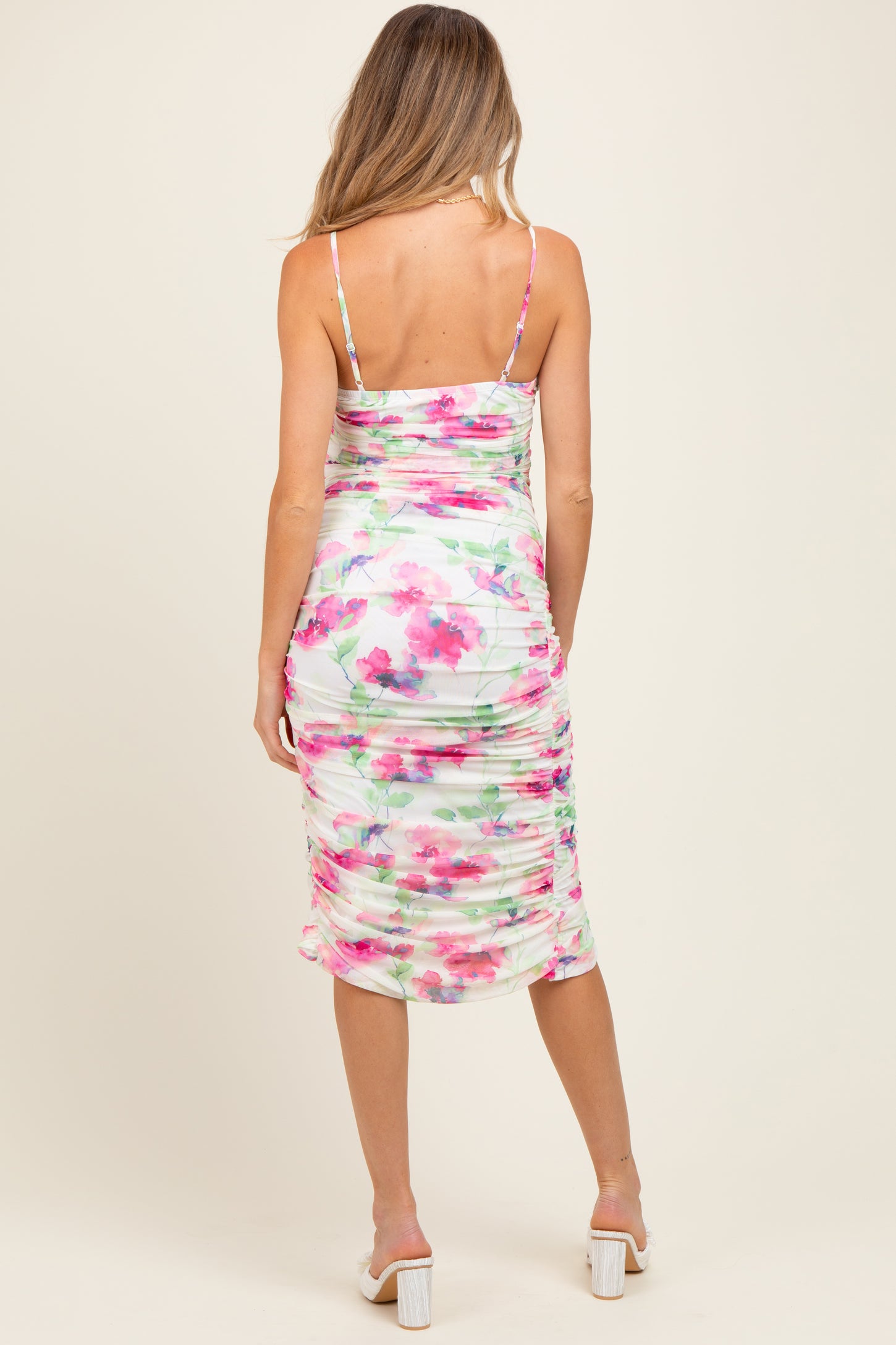 woman wearing a floral ruched maternity dress with adjustable straps, showing the back view