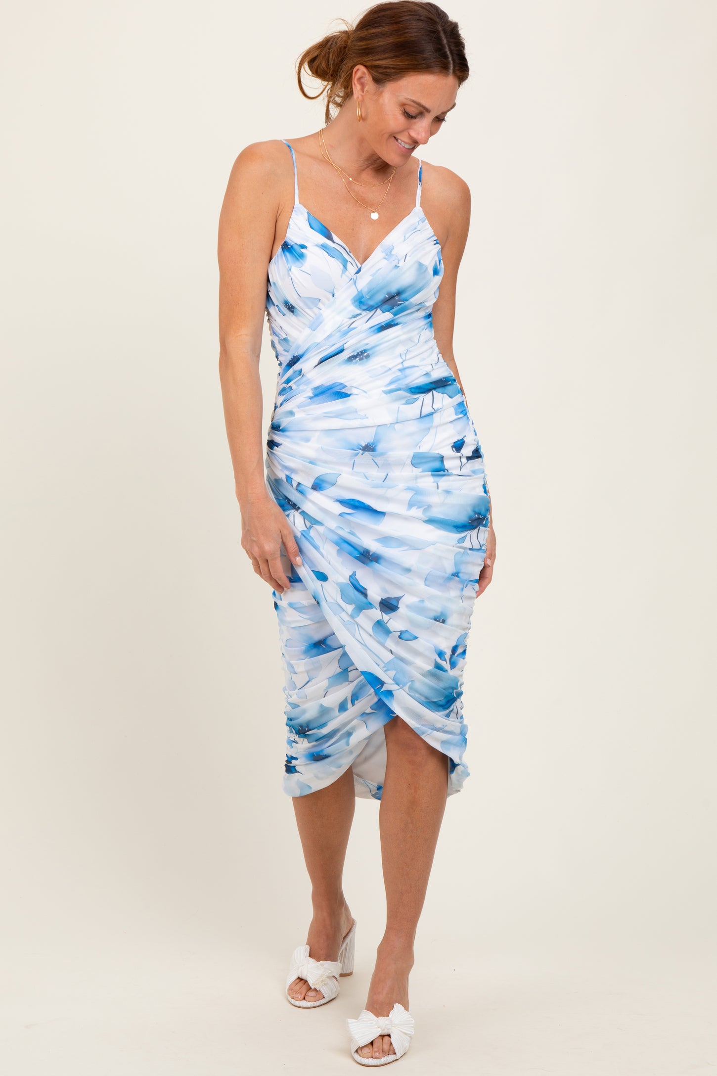 woman wearing a fitted blue and white watercolor print dress with spaghetti straps and a side ruching detail