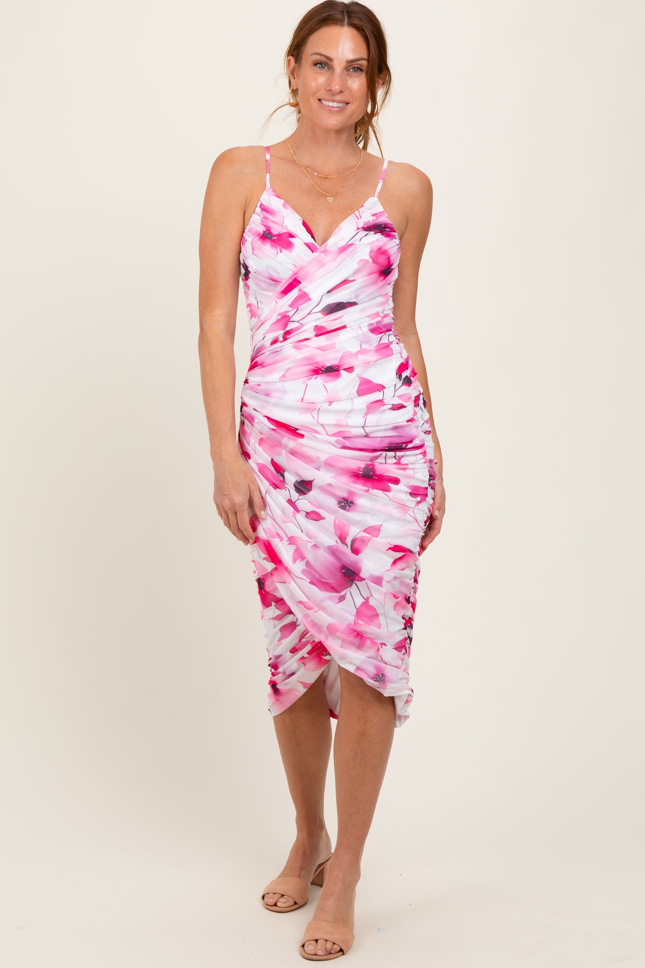 woman wearing a pink and white floral print spaghetti strap dress with a gathered detail at the waist