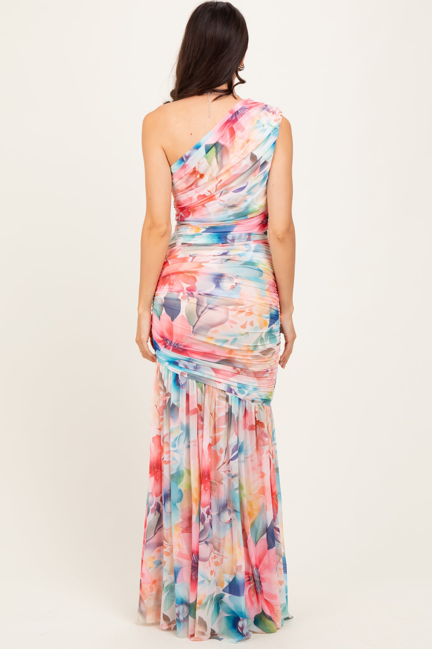 woman wearing a floral print one-shoulder maxi dress with a fitted bodice and flowing skirt