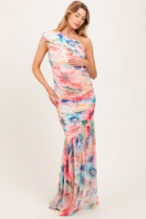 woman wearing a floral one-shoulder maternity gown with a fitted silhouette and flowing skirt, showcasing a baby bump