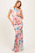 woman wearing a floral one-shoulder maternity gown with a fitted silhouette and flowing skirt, showcasing a baby bump