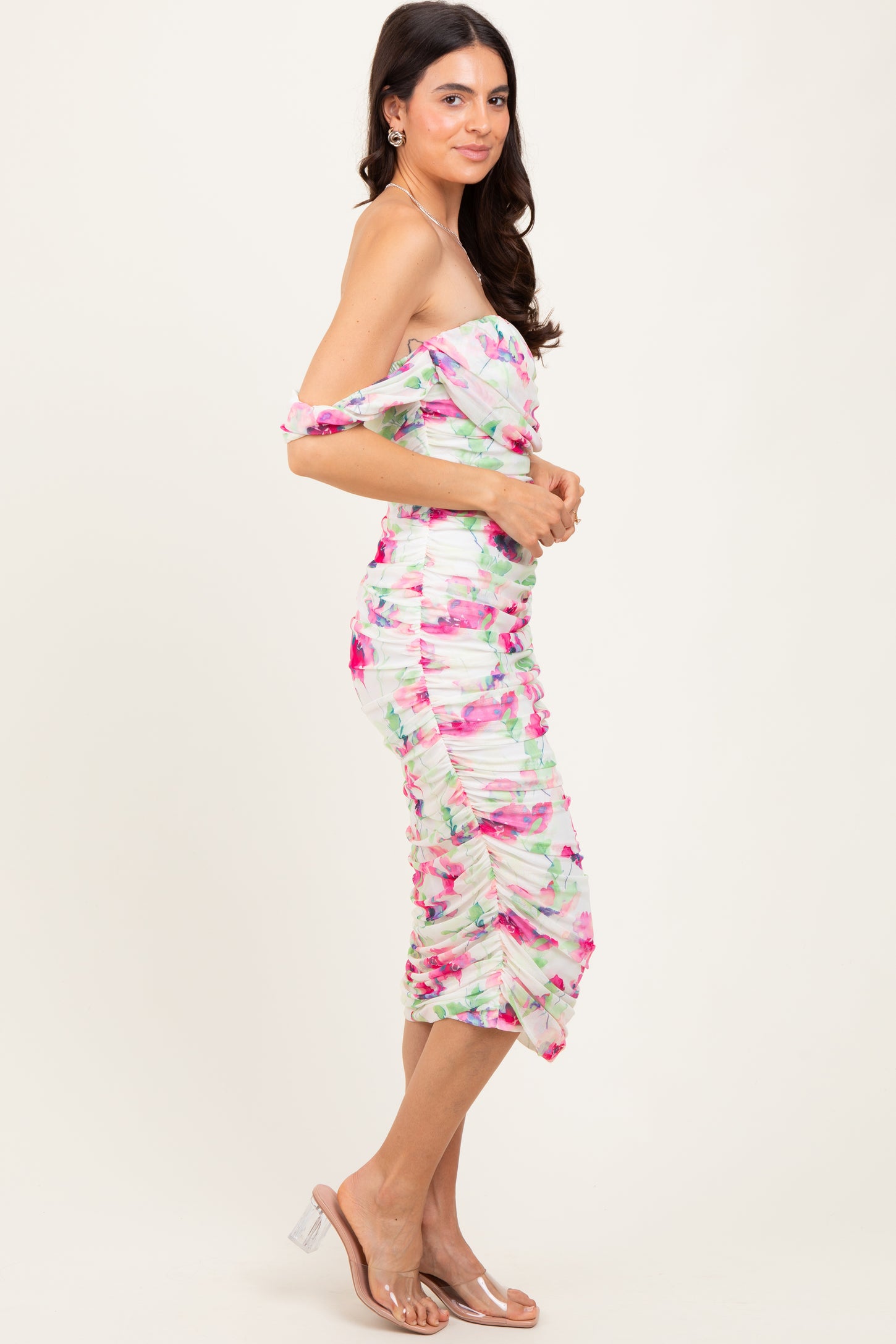 woman wearing a colorful off-the-shoulder fitted dress with ruched details and a midi length