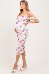 woman wearing a floral off-the-shoulder maternity dress with ruching and a visible baby bump