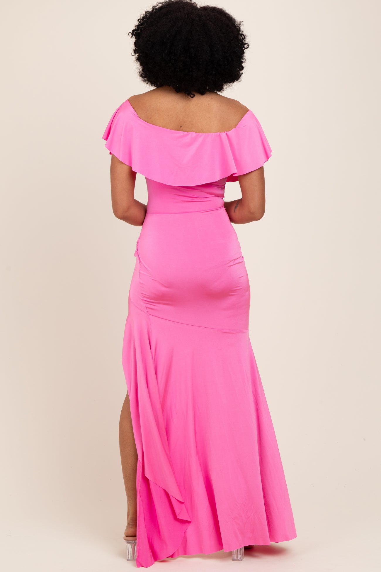 woman wearing a bright pink off-the-shoulder maxi dress with a ruffled neckline and a flowing skirt