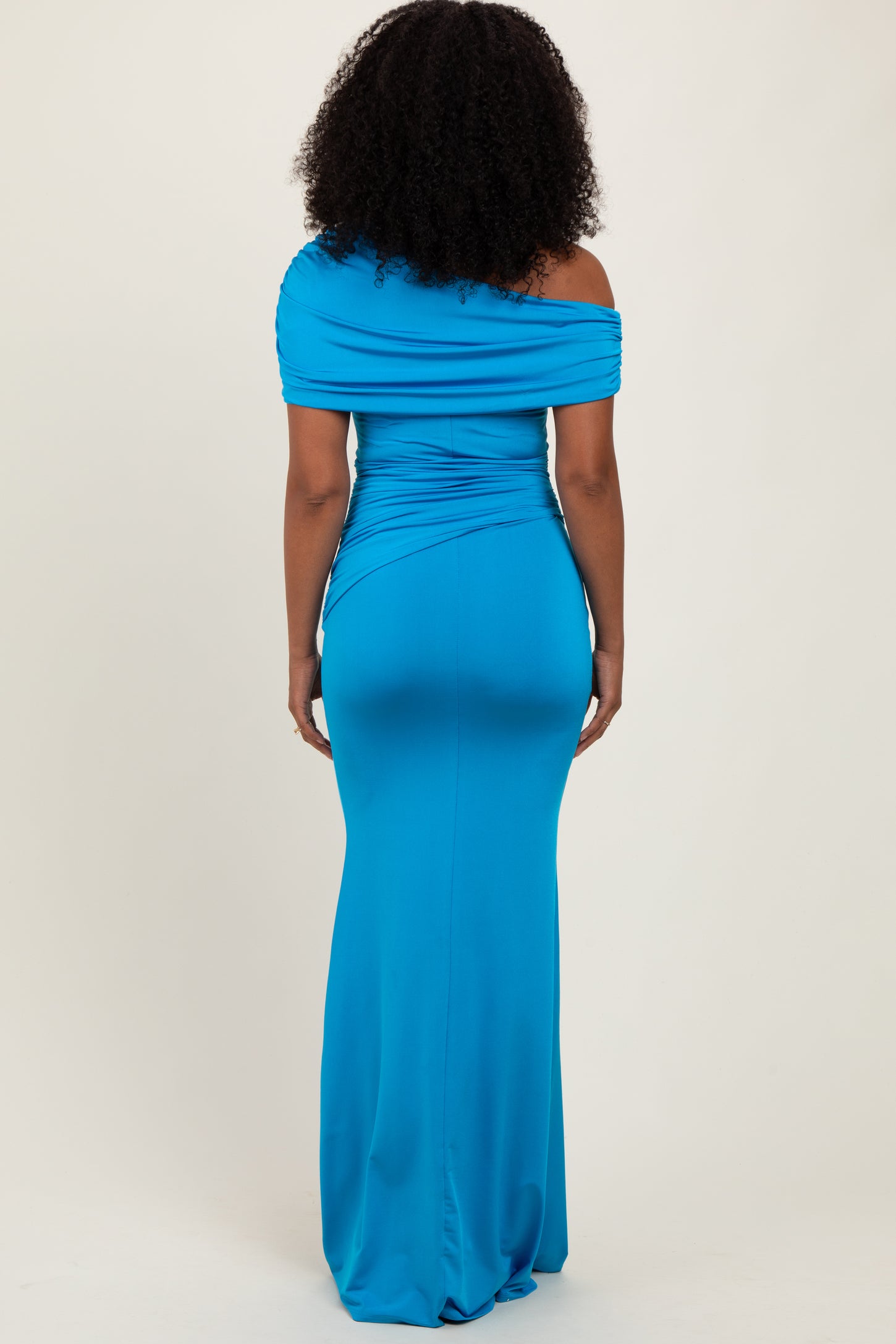 woman wearing a fitted off-the-shoulder bright blue maxi dress from the back