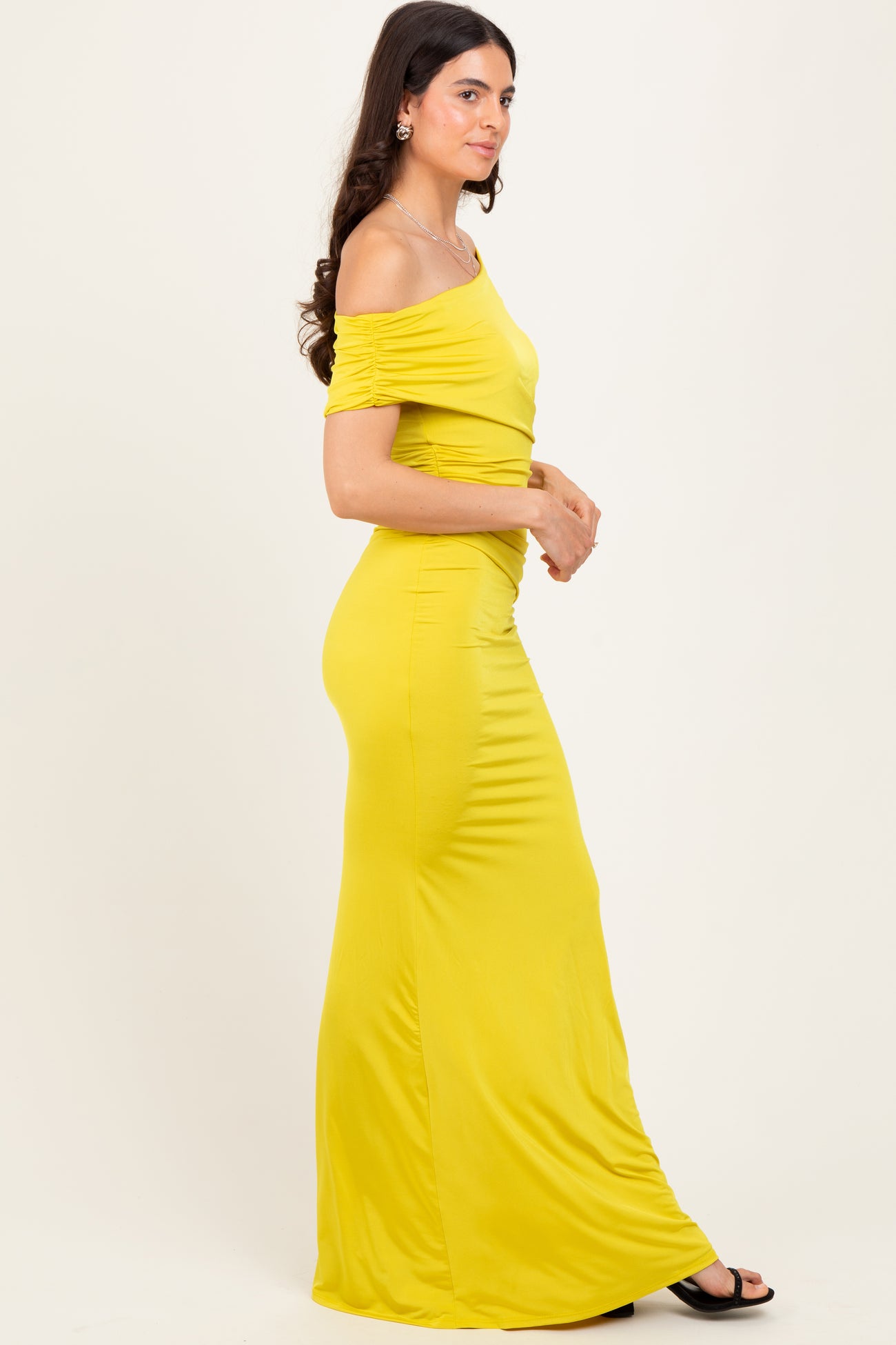 woman wearing a bright yellow off-shoulder maxi dress with ruched detailing and a fitted silhouette
