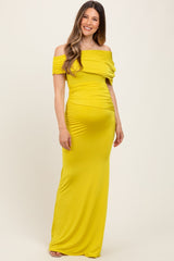 woman wearing a bright yellow off-the-shoulder maternity gown that accentuates her baby bump