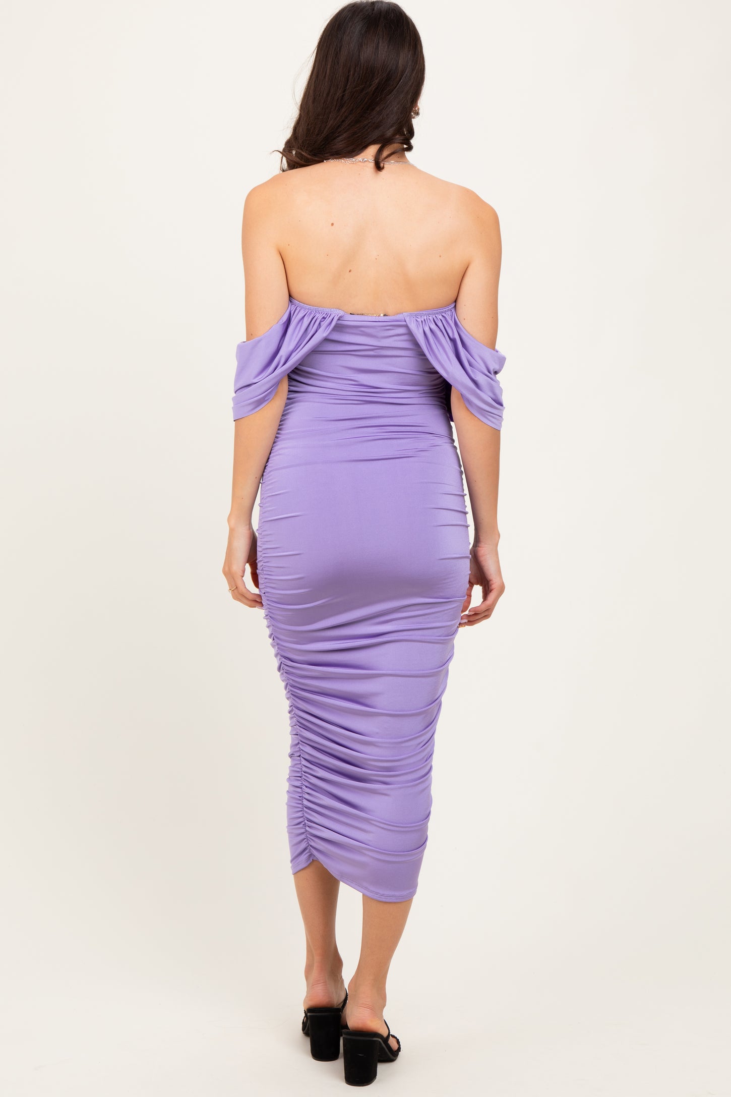 woman wearing a form-fitting lavender off-the-shoulder dress with ruching detail and a midi length