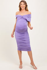 woman wearing a lavender off-shoulder maternity dress with ruched detailing and a visible baby bump