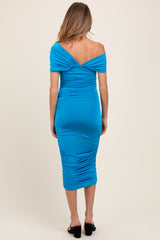 woman wearing a sleeveless bright blue off-the-shoulder maternity dress with ruching and a fitted silhouette