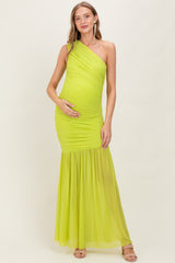 woman wearing a bright neon green one-shoulder maternity gown with ruched detailing and a flowing skirt, showing her baby bump