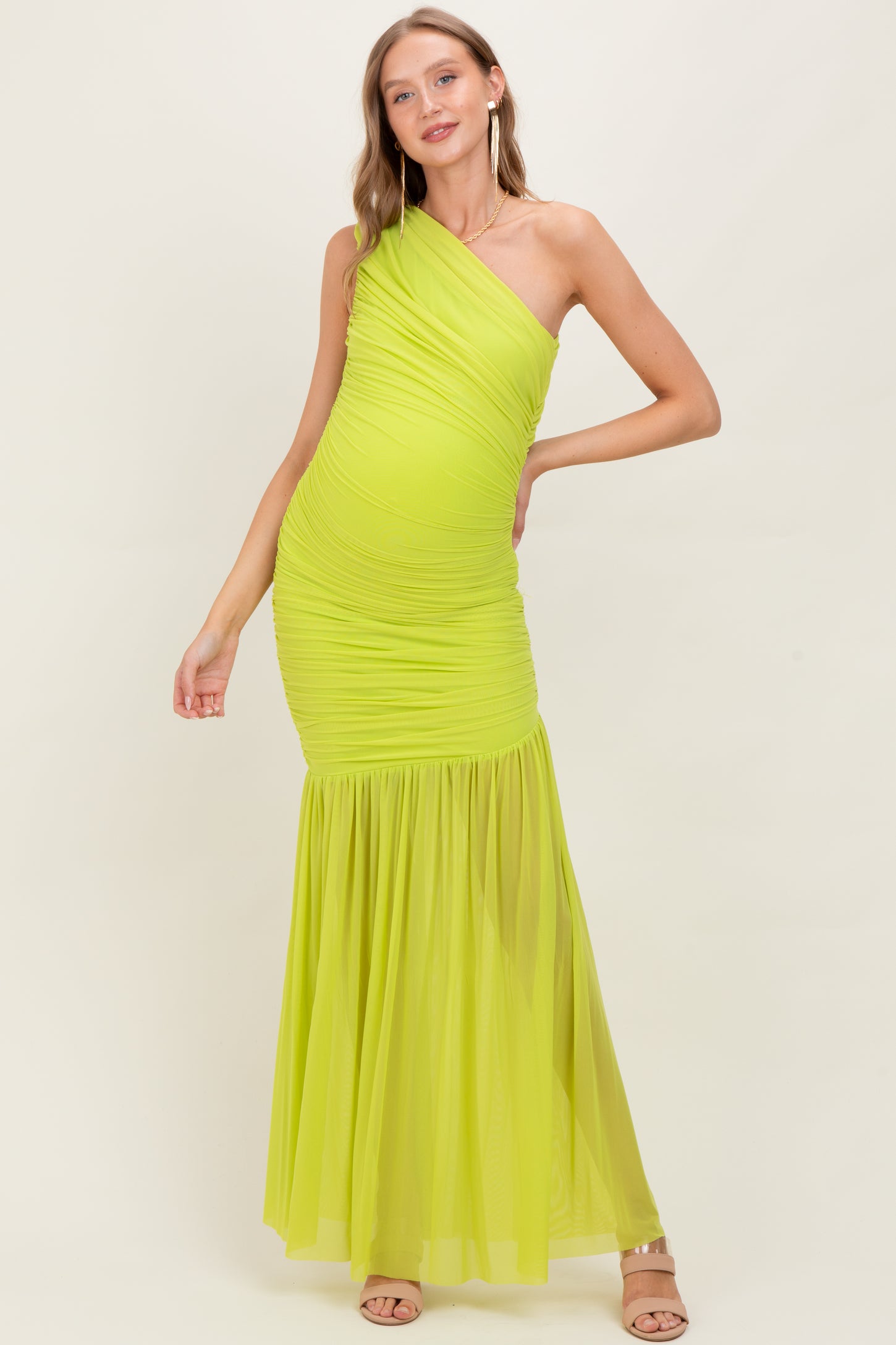 woman wearing a bright yellow one-shoulder maternity dress with ruched detailing and a flowing skirt, showcasing her baby bump