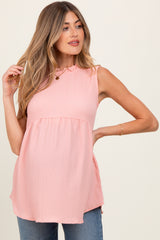 woman wearing a light pink maternity top with a tied neckline and flowy silhouette, displaying her baby bump