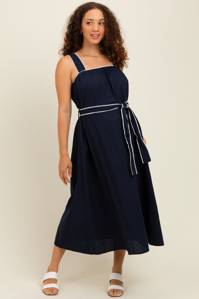 woman wearing a navy blue maternity dress with a square neckline and waist tie detail