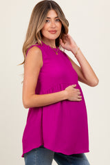 woman wearing a fuchsia sleeveless maternity top with ruffle detail and holding her baby bump