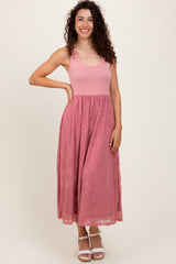 woman wearing a pink maxi dress with a fitted top and lace skirt, smiling and posing with one hand on her hip