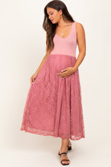 woman wearing a pink lace maternity dress and holding her baby bump