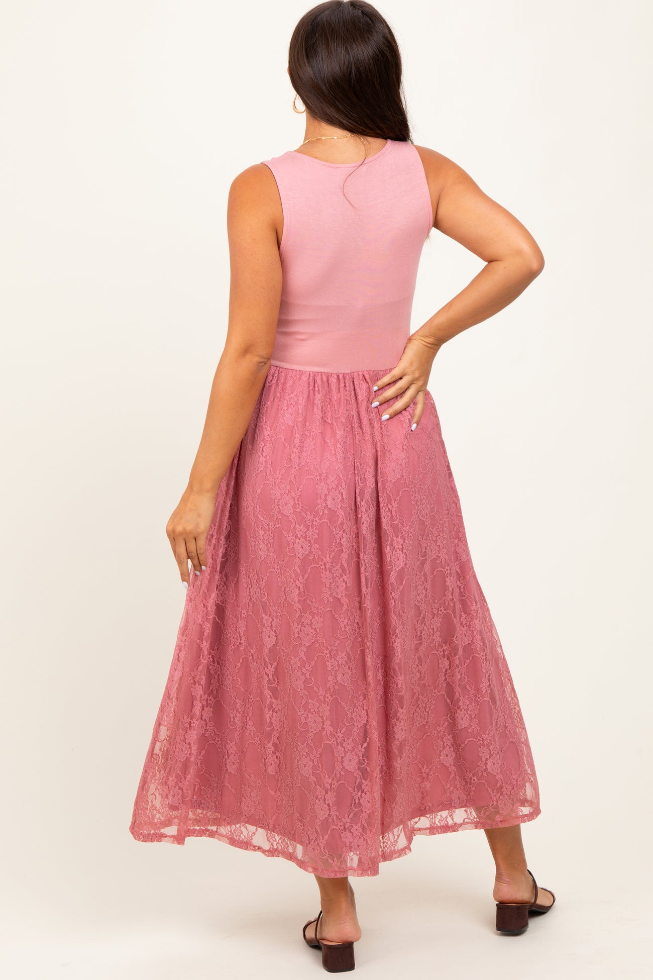 woman wearing a pink maternity dress with a fitted top and flowing lace skirt, showcasing a baby bump