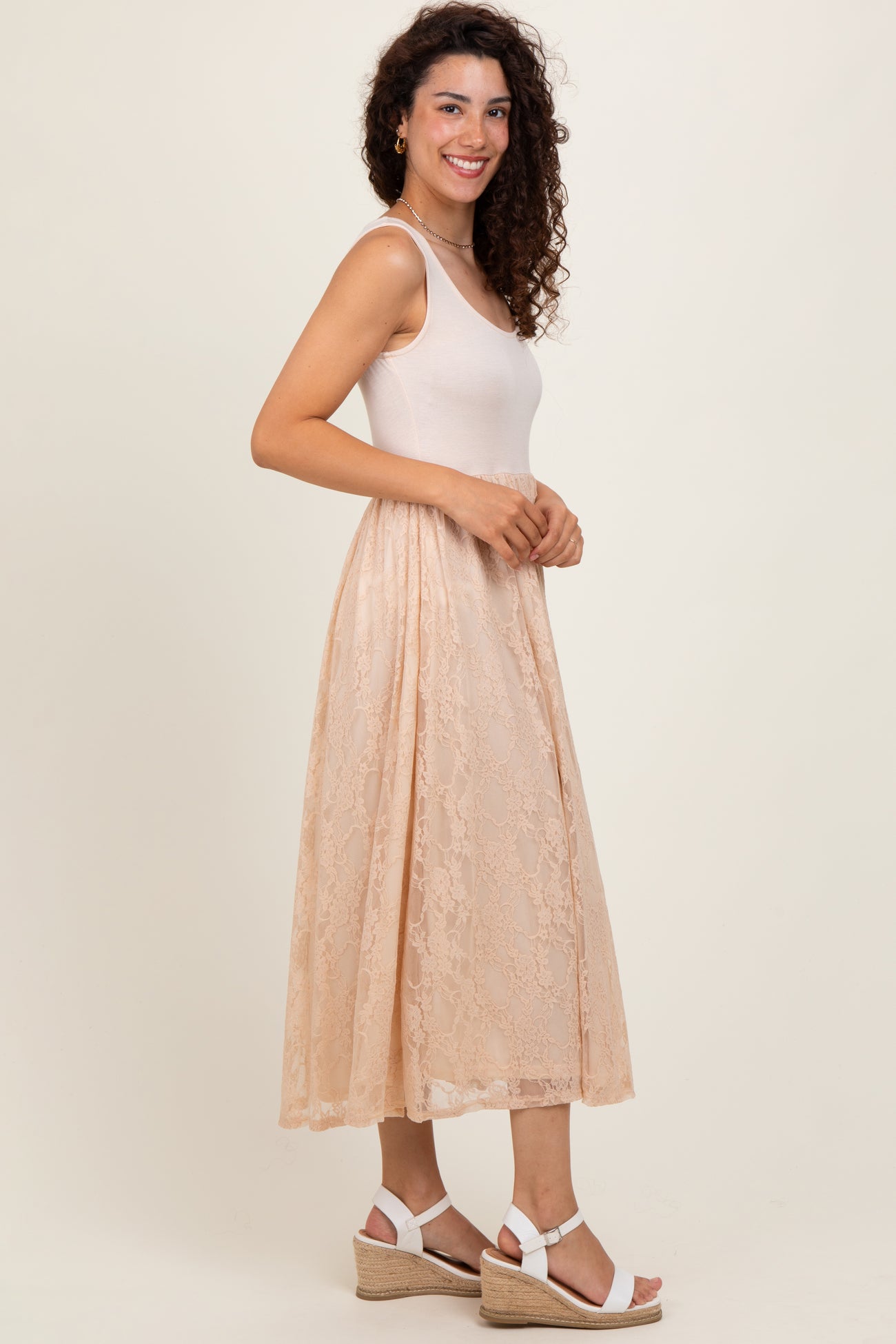 woman wearing a beige fitted tank dress with a lace overlay and white wedge sandals