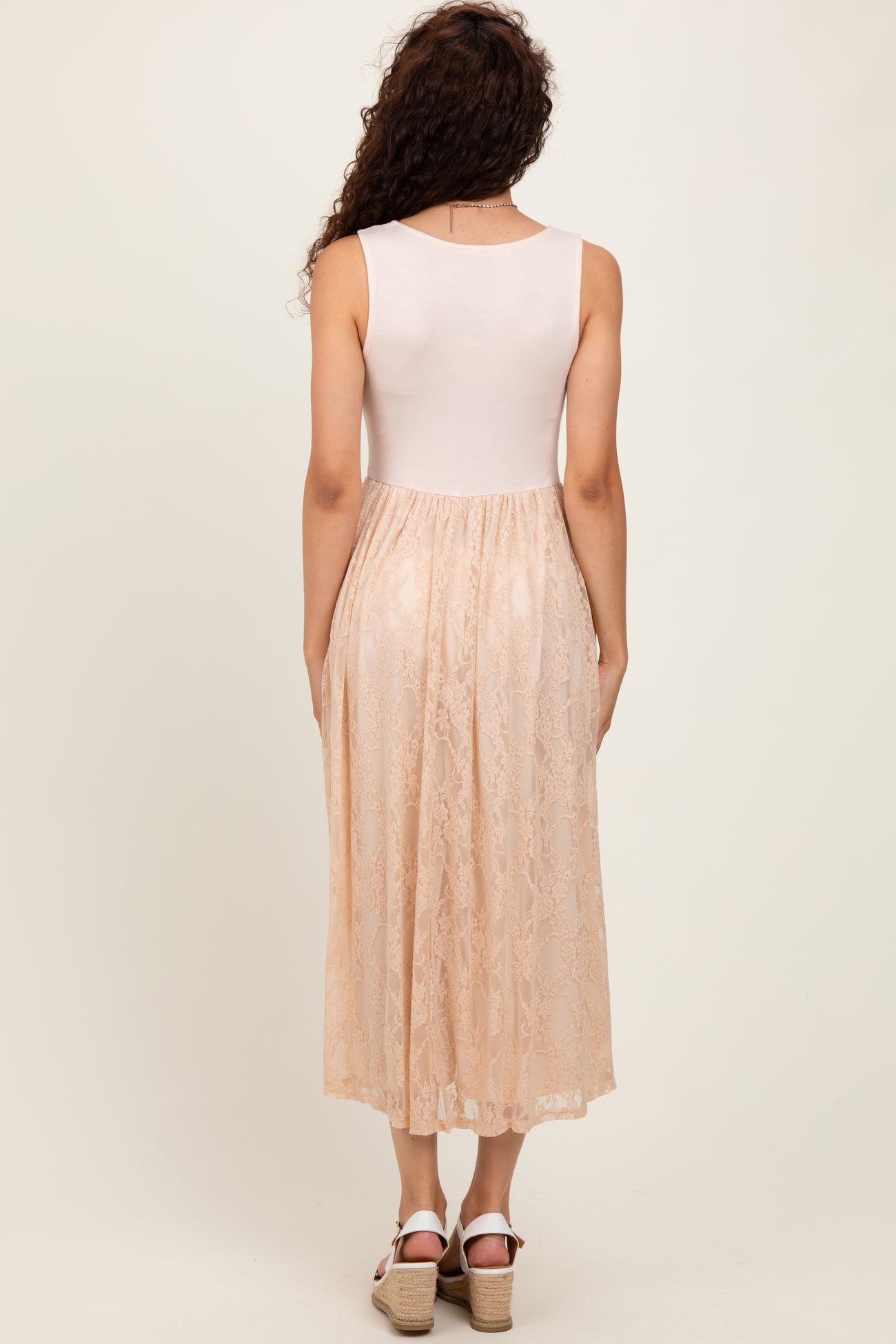 woman wearing a back view of a midi dress with a fitted white top and a sheer lace peach skirt
