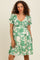 woman wearing a green floral maternity dress with short puff sleeves and a smocked bodice