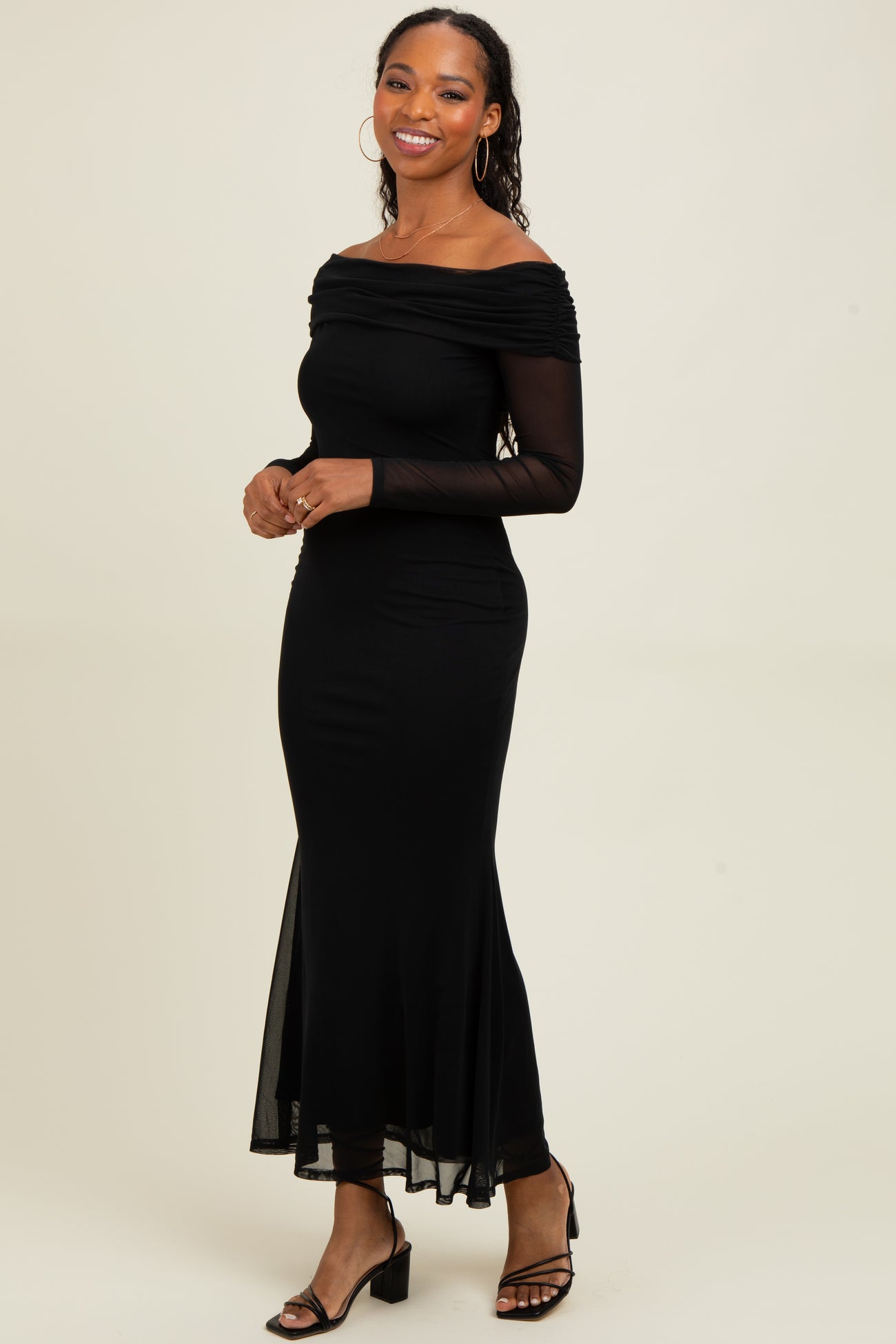 woman wearing a black off-the-shoulder long sleeve dress with a fitted bodice and a flowy hemline